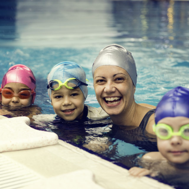 Swimming instructor having fun with group of children